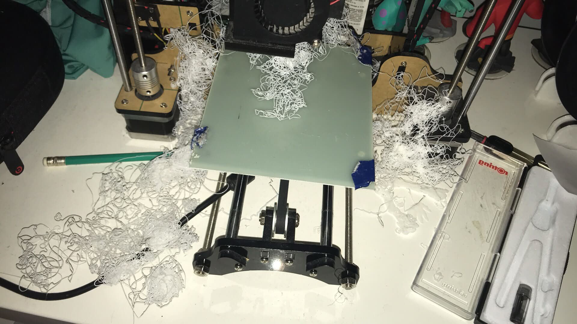 The print bed buried in a nest of tangled white filament. A failed print that came loose mid-job and kept extruding into mid-air.